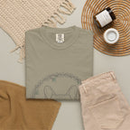 Botanical Frenchie tee folded flat with a candle, jeans, and a woven placemat