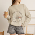 Woman wearing the sand Sunday Morning Sofa Club crewneck while holding an iced coffee