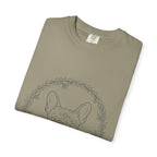 Close-up of the French bulldog and leaf wreath print on a folded sandstone tee