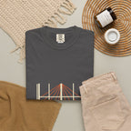 Shadow & Sunlight tee folded flat with a candle, jeans, and a woven placemat