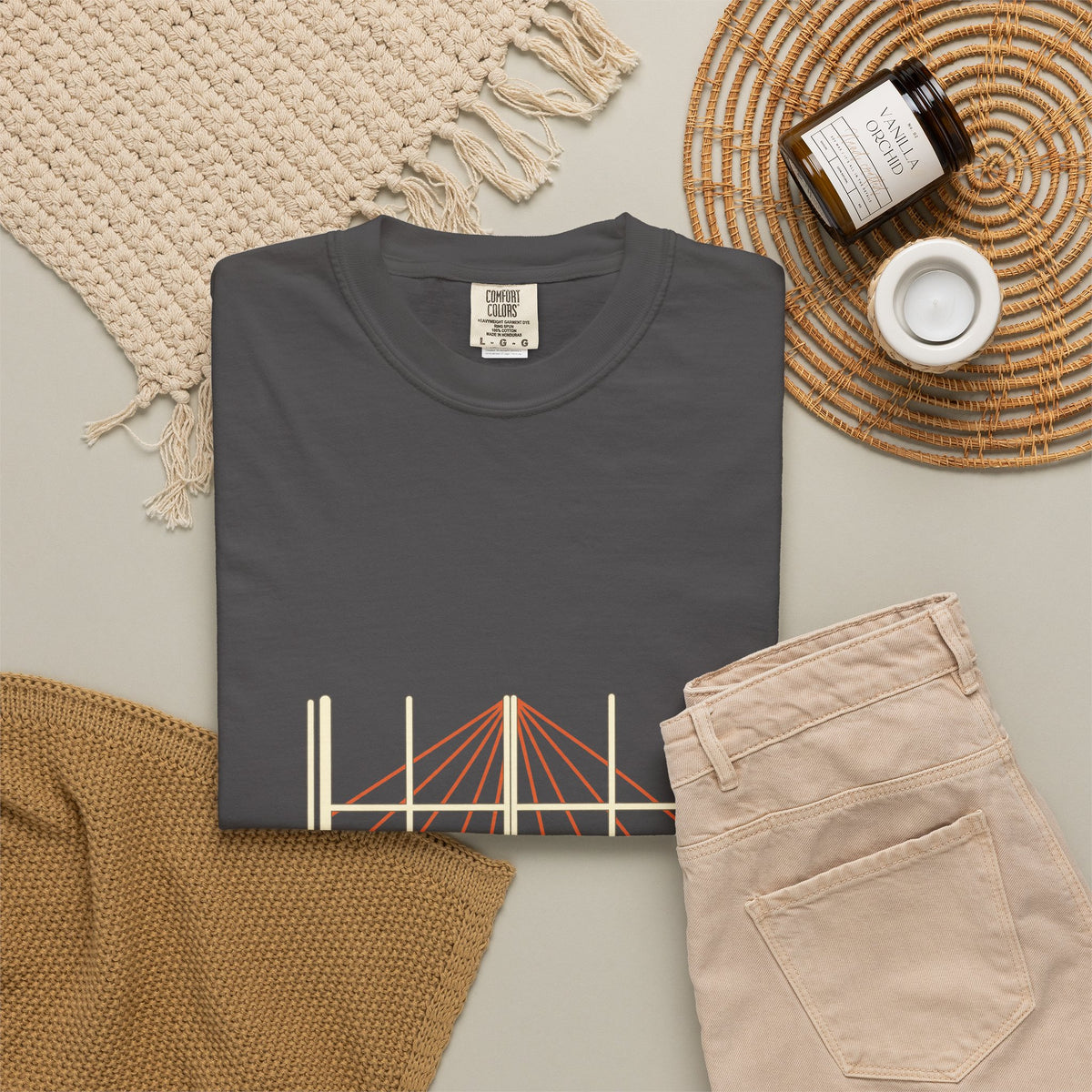Shadow & Sunlight tee folded flat with a candle, jeans, and a woven placemat