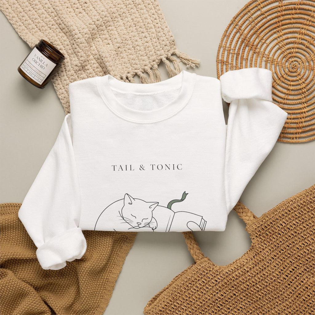 White Quiet Company crewneck folded flat with a candle, woven placemat, and knit throw